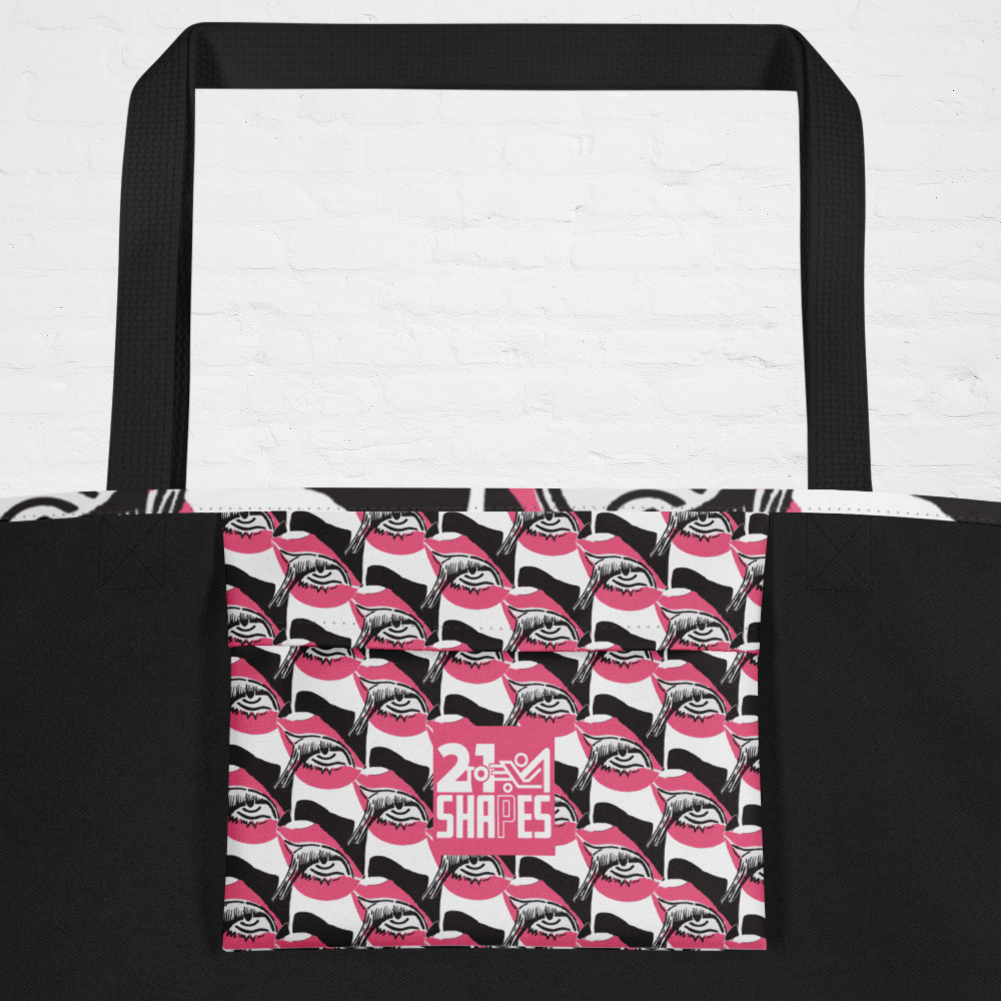 Tote bag inside pocket with black, white and pink design of a repeating eye with the 2-to-1 Shapes brand logo